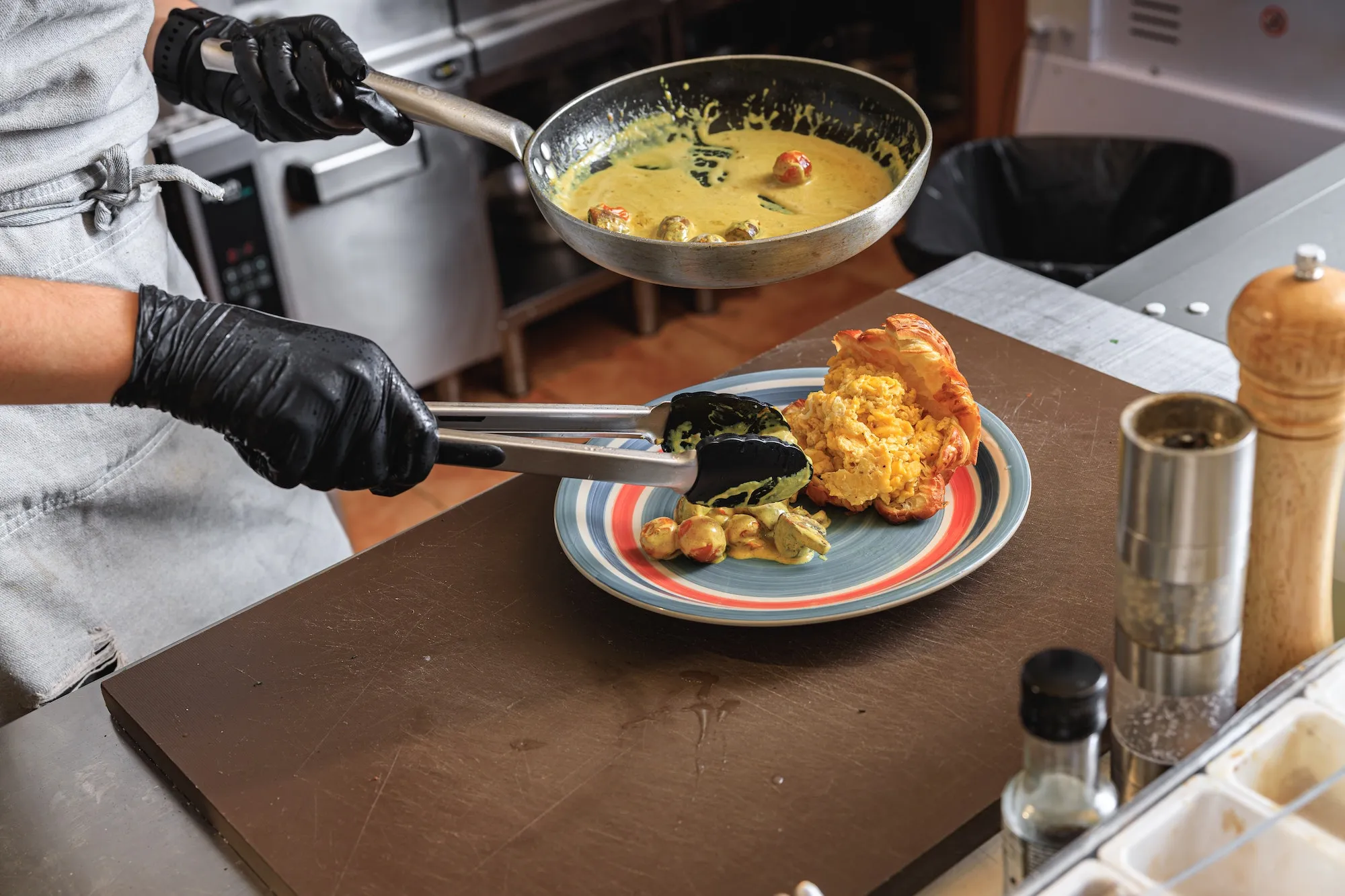 close-up-of-chef-putting-dish-from-frying-pan-into-the-plate-before-serving-to