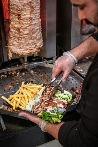 Chef preparing shawarma with fries and salad, showcasing Moroccan street food.